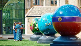 3 women admiring the brightly coloured globes in Rhodes House garden