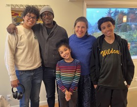 Photo of a smiling family, 5 people pictured.