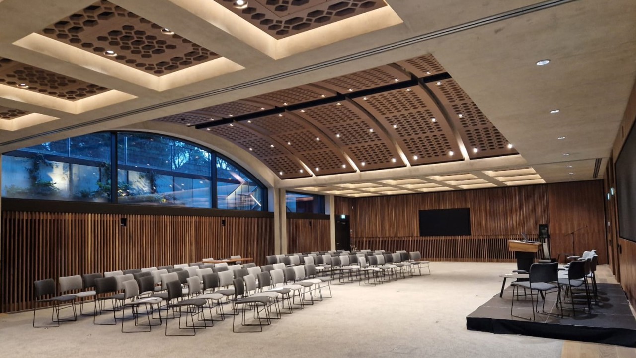 Rhodes House Conference Hall set up for a meeting with theatre style seating and stage with speaker chairs and lectern