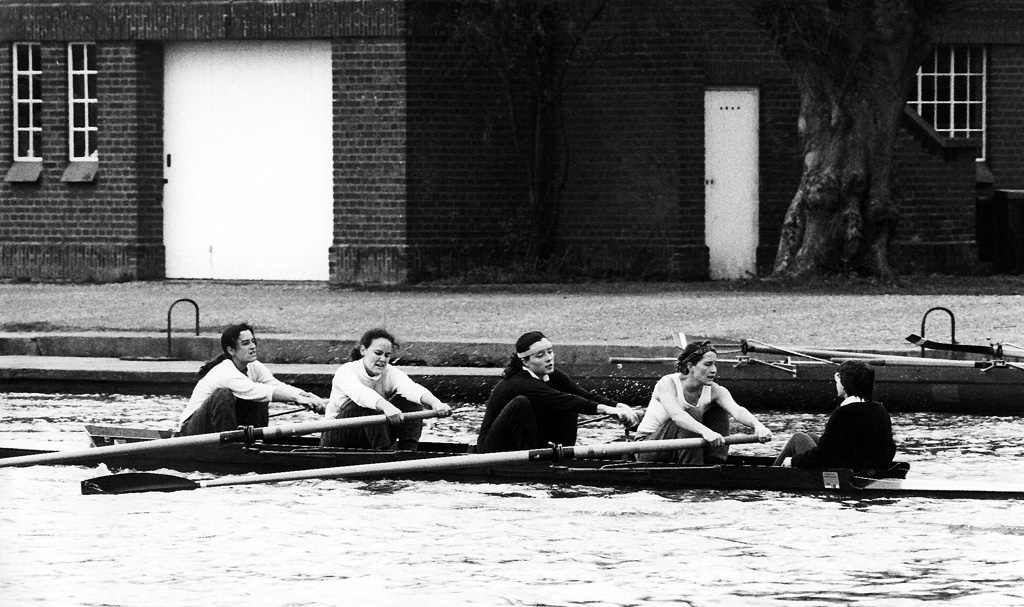 Balck and white photo of a group of 5 female rowers mid competition.
