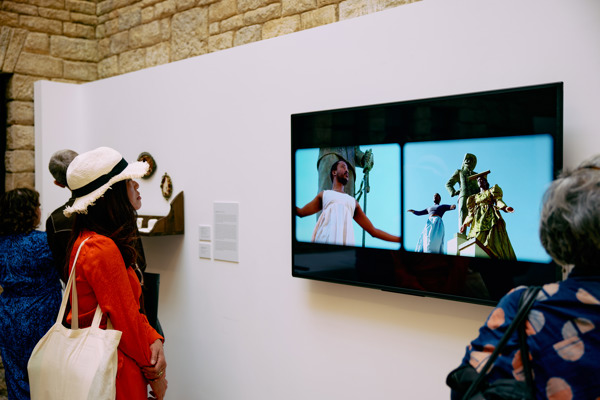 A woman watching a film titled Man of War: Leave My House by Gift Uzera, Muningandu Hoveka and Nicola Brandt
