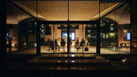 Looking inside the Glass Pavilion at night with delegates in a meeting.