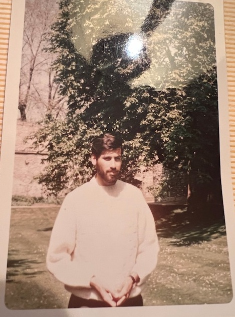 Richard wearing white jumper stood in a garden.