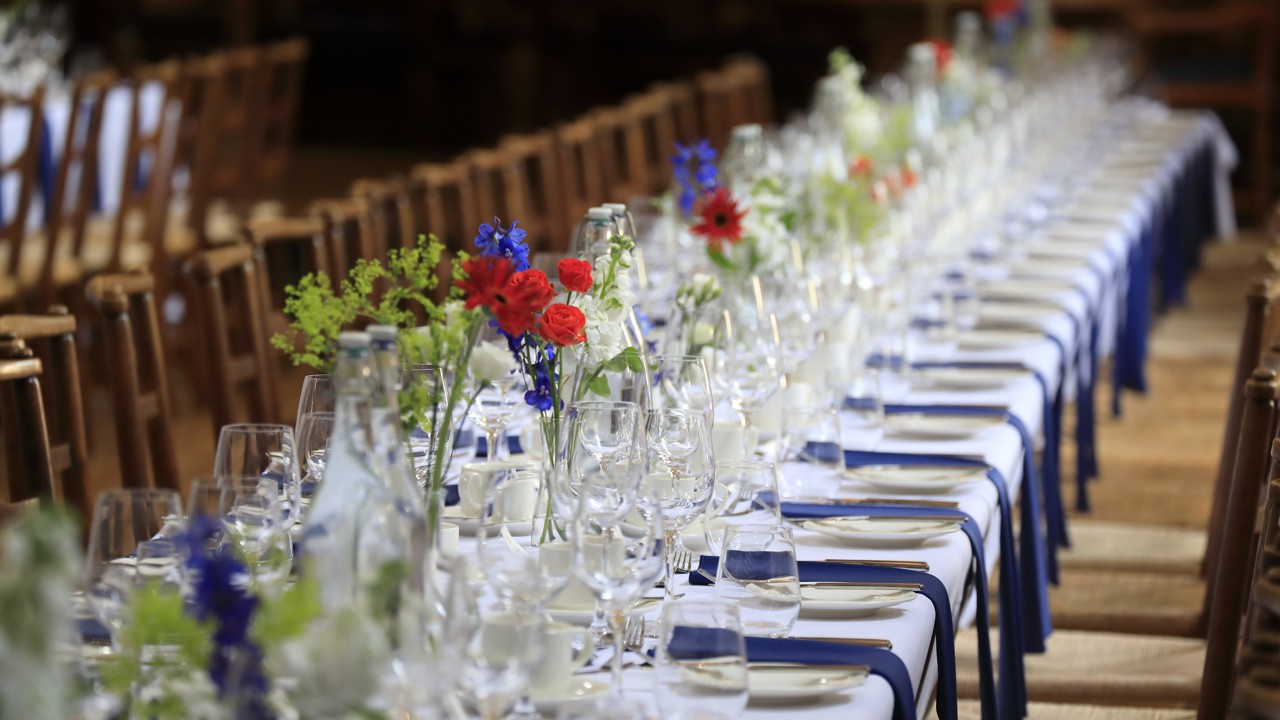 McCall MacBain Hall dining table with blue napkins and red & blue flowers