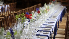 McCall MacBain Hall dining table with blue napkins and red & blue flowers
