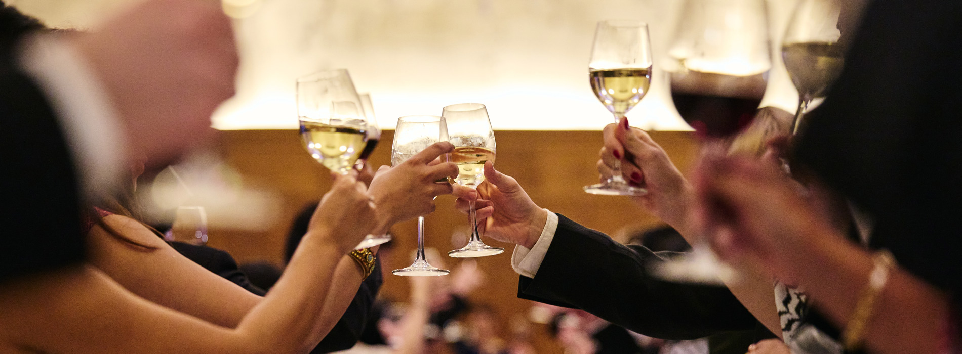 Hands raised with glasses of wine for a toast.