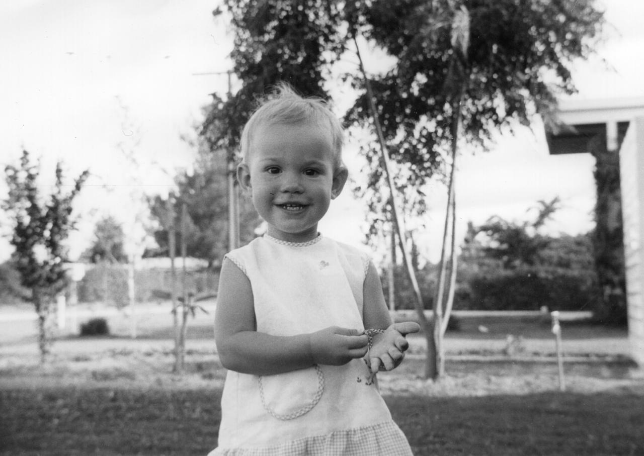 A black-and-white picture of Elle as a toddler with thin trees in the background