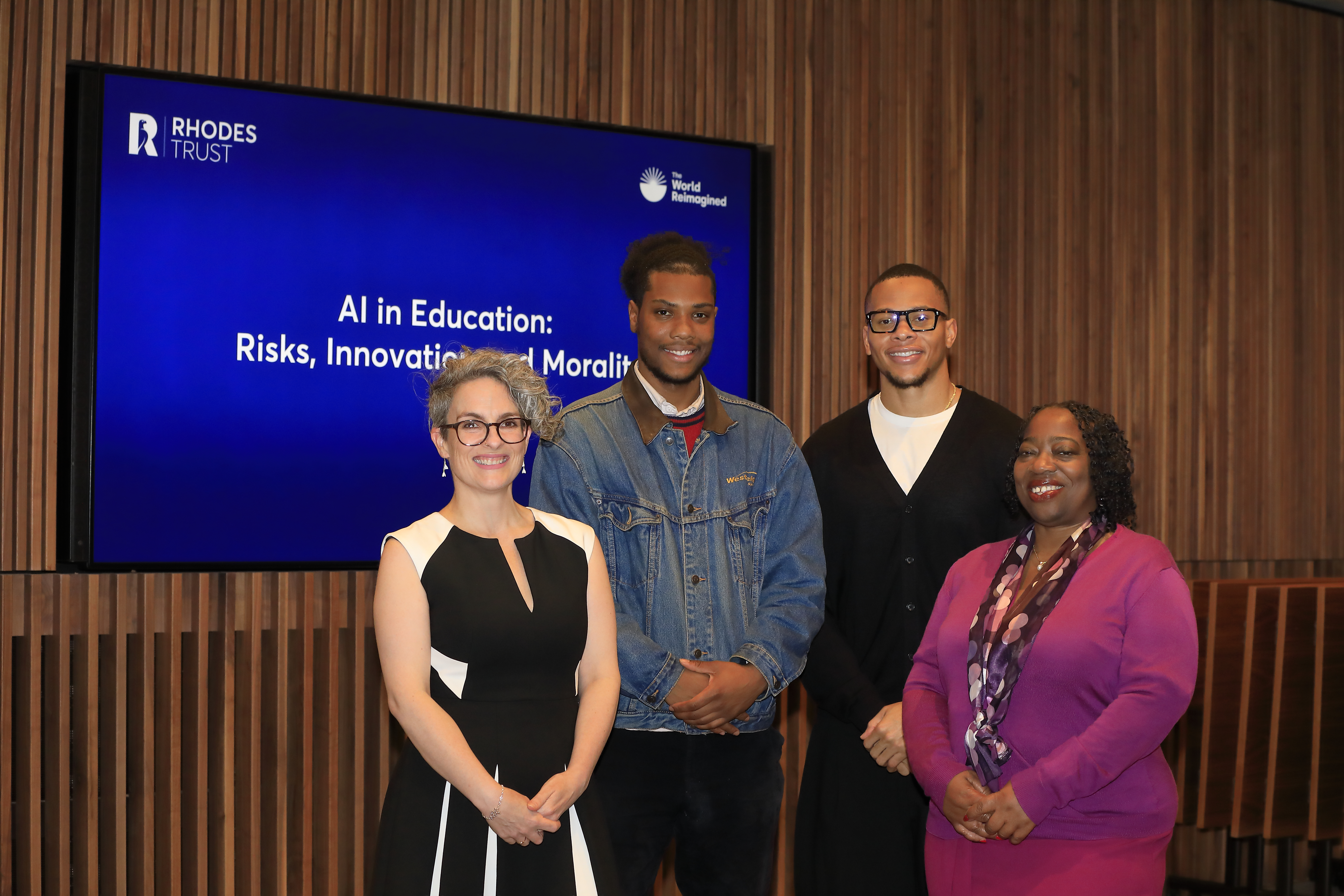 4 speakers posing for the camera in front of a blue screen
