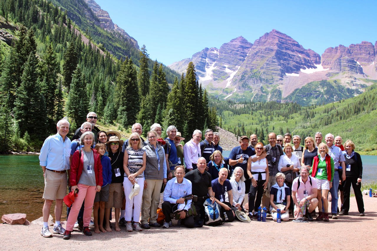Photo of a large group in the forest with mountains in the background.