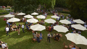 Rhodes House West Lawn with garden party guests and outdoor furniture and umbrellas, as seen from the first floor. Photo courtesy of Nasir Hamid.