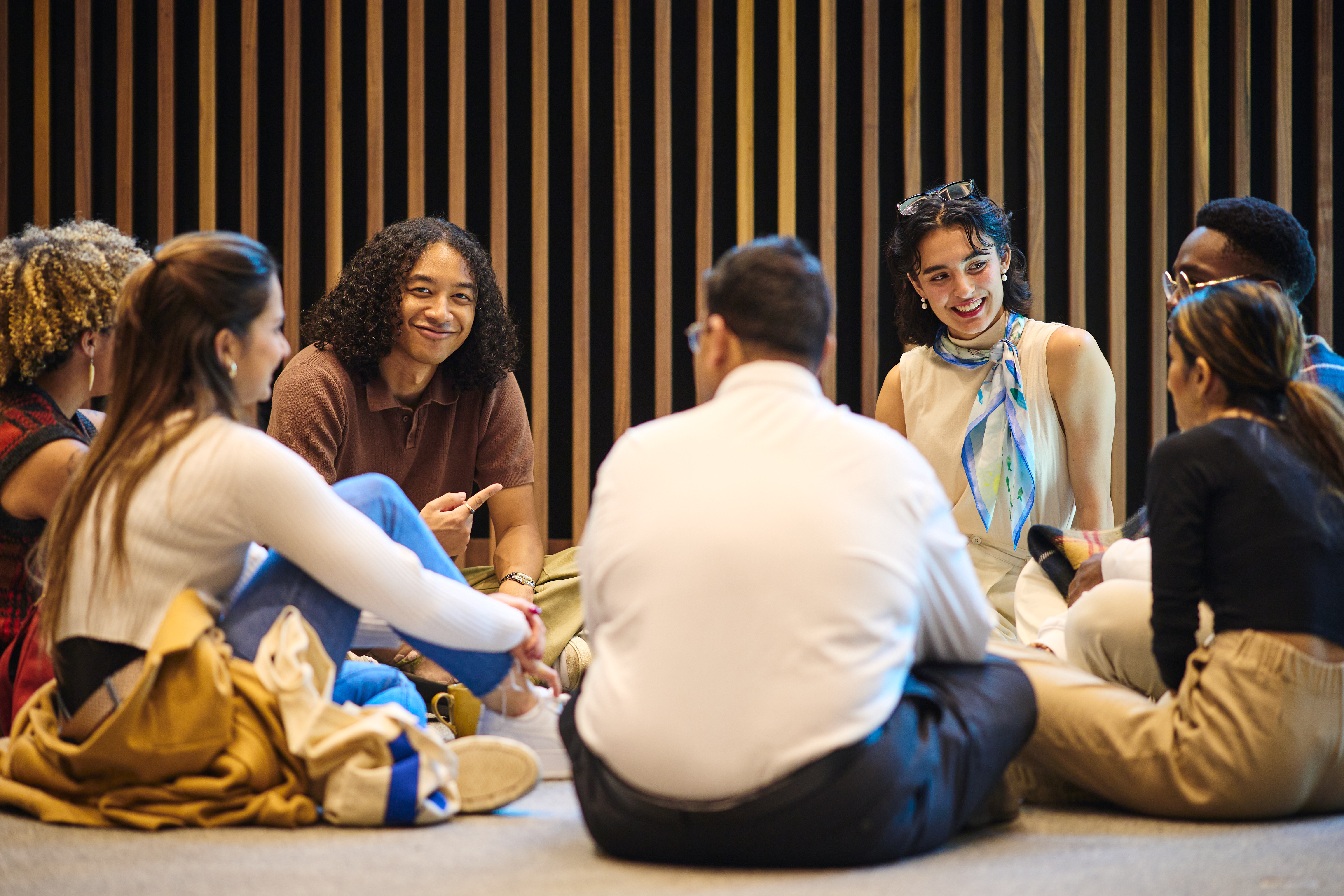A Group of Rhodes Scholars sitting in a circle on the floor and interaction with each other.