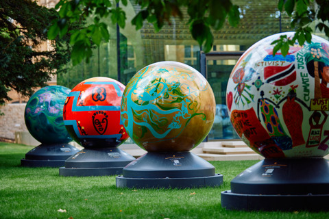 4 brightly coloured globes part of the World Reimagined exhibition in Rhodes House garden