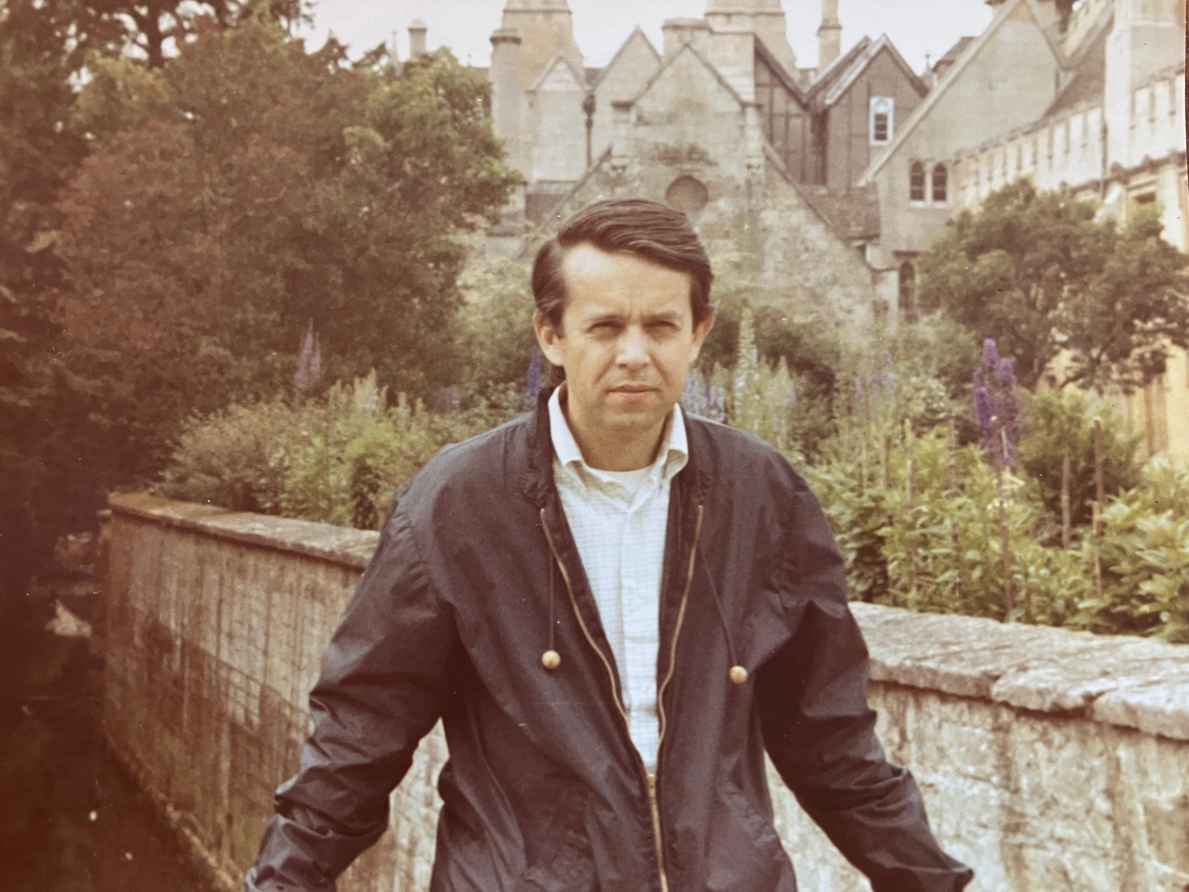The picture shows Paul in a leather jacket with trees in the background.