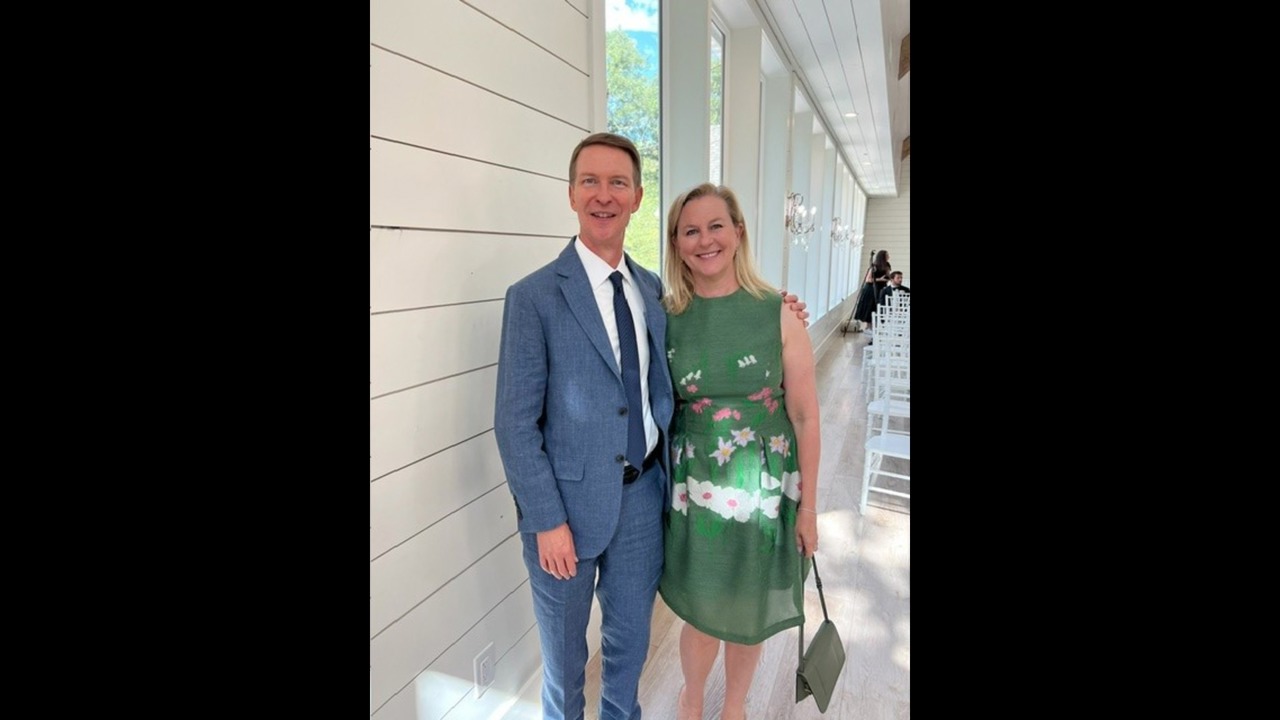 Bob in a blue suit with his wife in a green dress