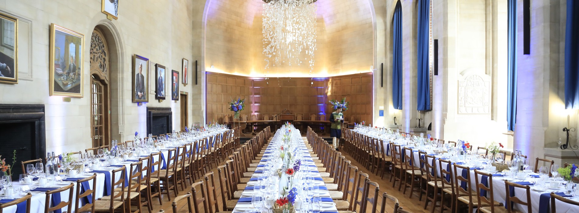 McCall MacBain Hall set up banquet style with blue napkins and red and blue flowers on the tables.