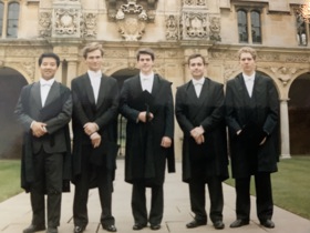 A group of 5 students stood in graduation attire before a building in Oxford.