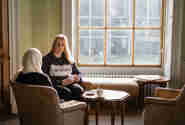 Two scholars talking by a window