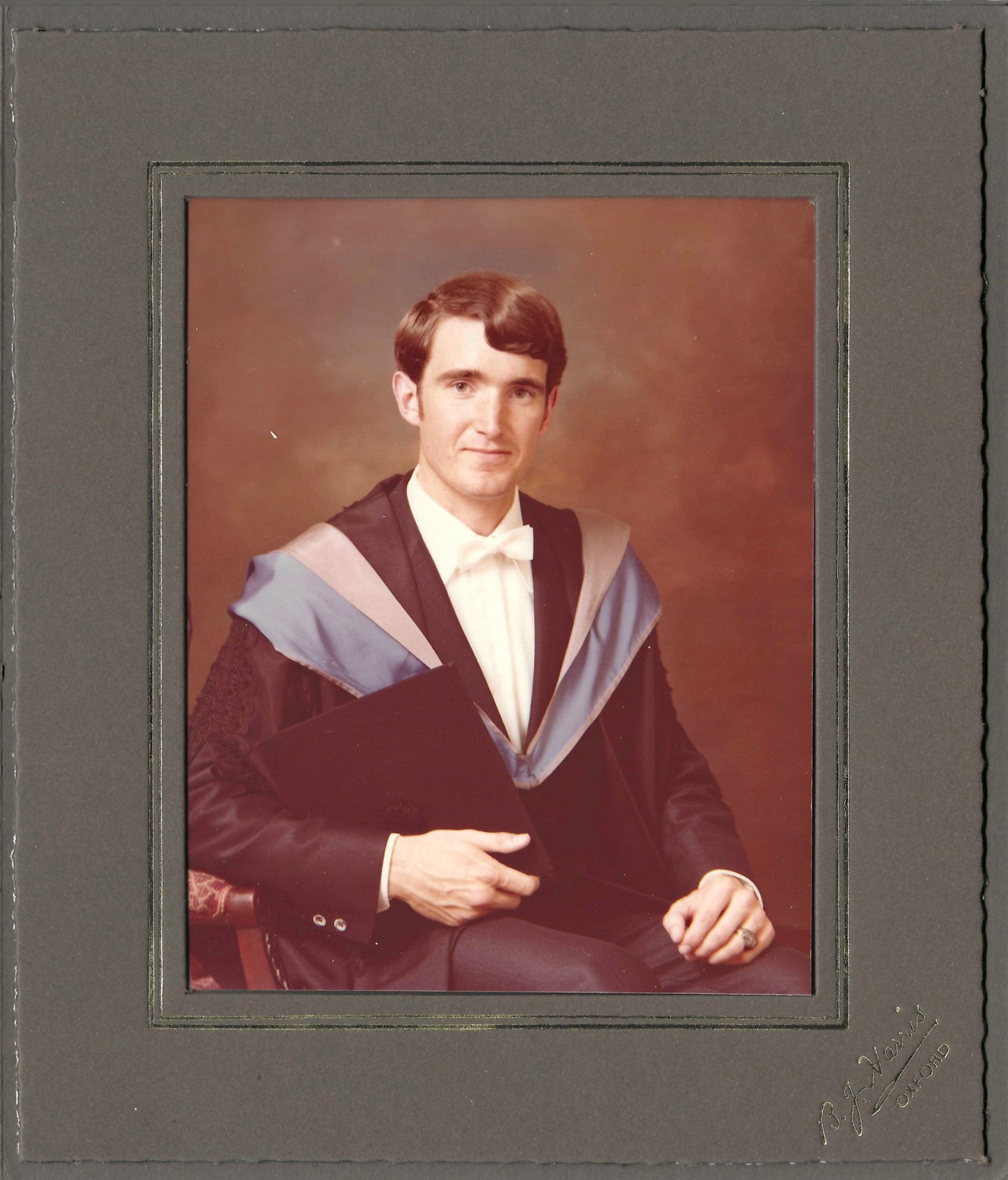 A framed photograph of John in a graduation gown