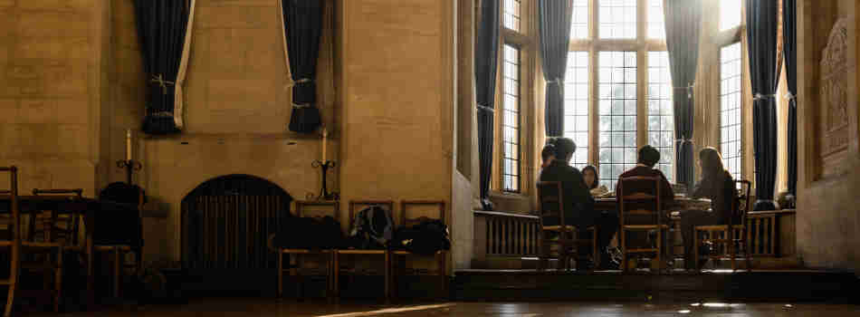 Scholars seated around a table in the bay window of Milner Hall