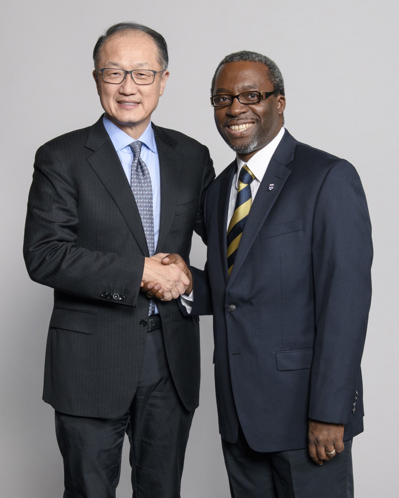 Kenneth stood on the right standing and shaking hands with man to the left.