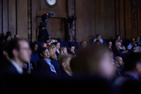 The picture shows Philip seated amongst a big crowd of people. He is listening intently.