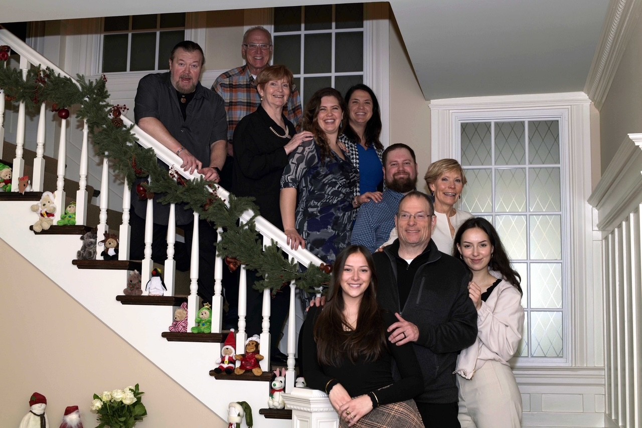 A group of people standing on a white staircase. They are all smiling. 