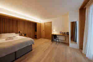 A Whole Room Shot Of One Of The Spacious Accessible Bedrooms In The Residential Courtyard The Floor And Focal Wall Are Lined With Wooden Panels