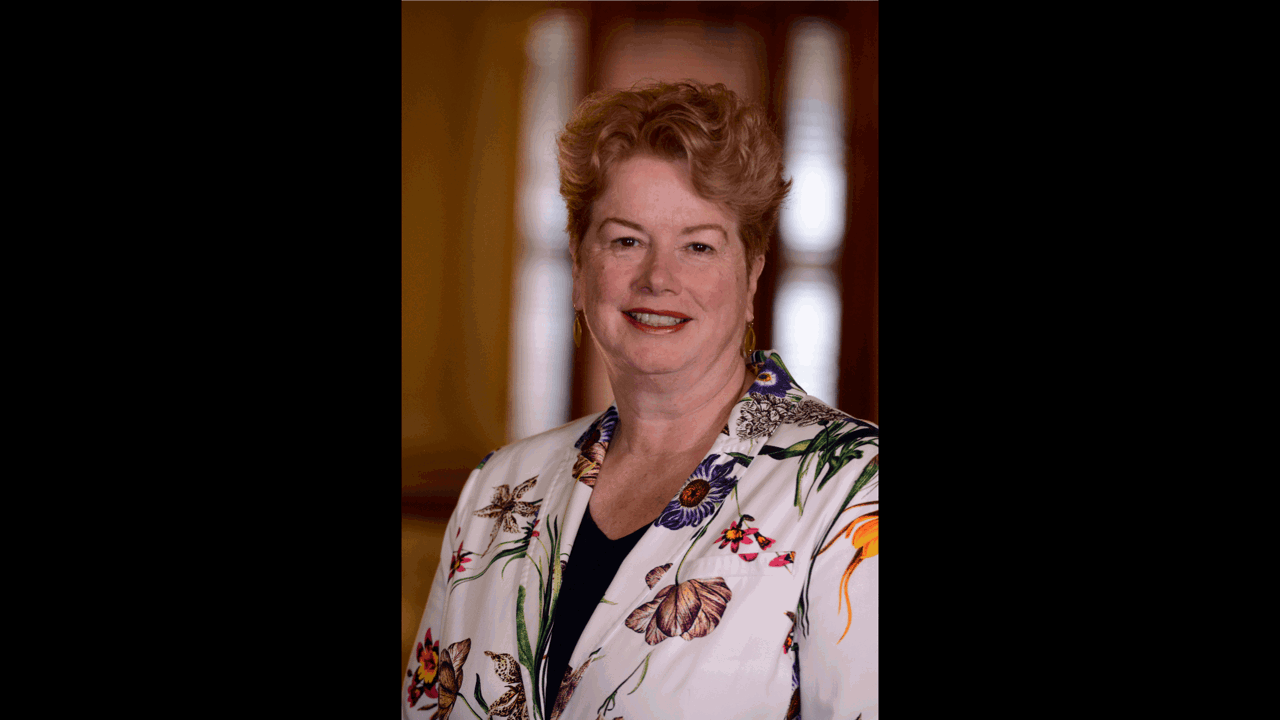 A picture of Elizabeth smiling and in a floral jacket