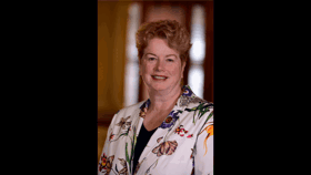 A picture of Elizabeth smiling and in a floral jacket