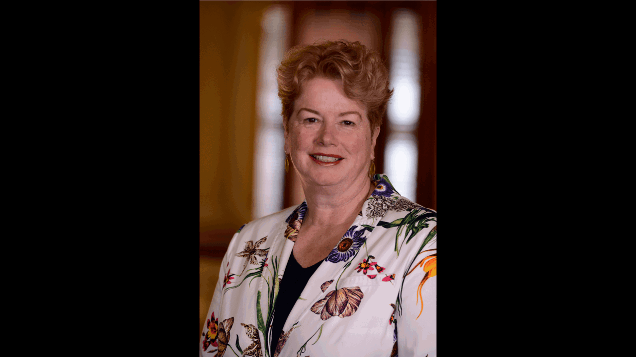 A picture of Elizabeth smiling and in a floral jacket