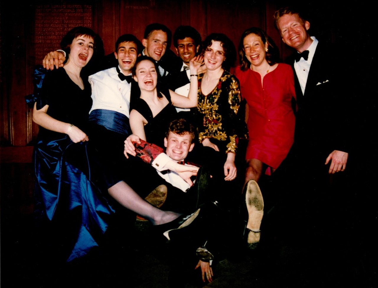 A picture of young students dressed in suits and dresses, laughing at the camera and in good spirits.