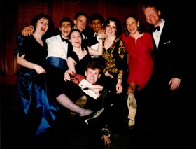 A picture of young students dressed in suits and dresses, laughing at the camera and in good spirits.