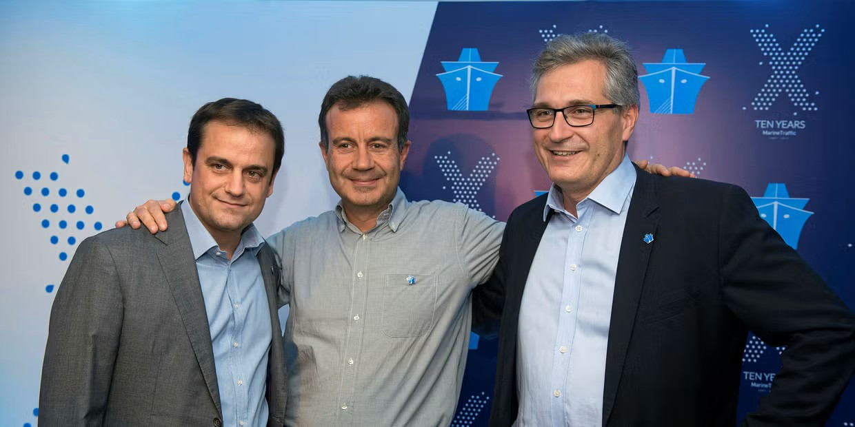 Argyris is stood to the right of two men. They are posing before a corporate banner which reads 'Ten Years Marine Traffic'