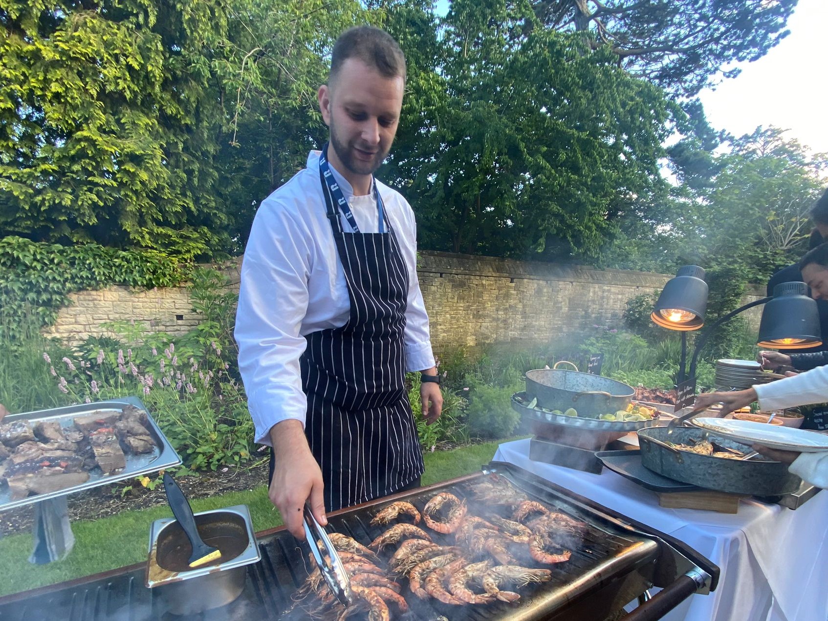 Chef grilling shrimp outside on the BBQ for a Rhodes House event.