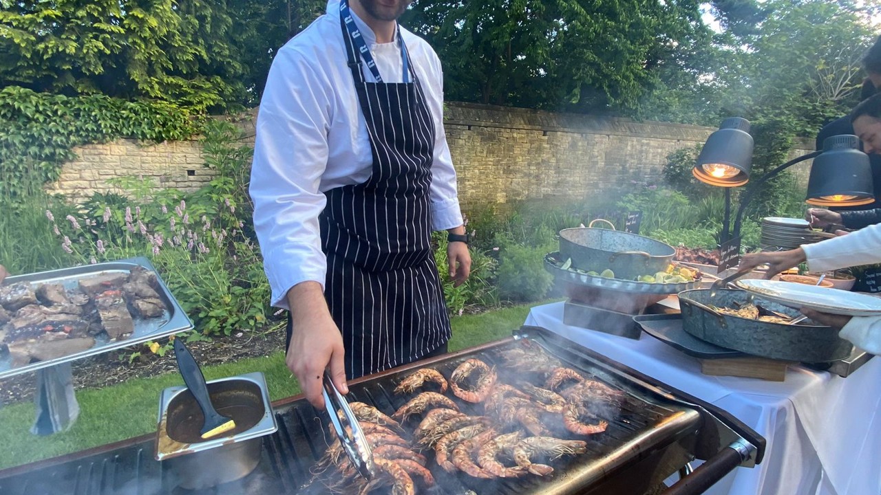 Chef grilling shrimp outside on the BBQ for a Rhodes House event.