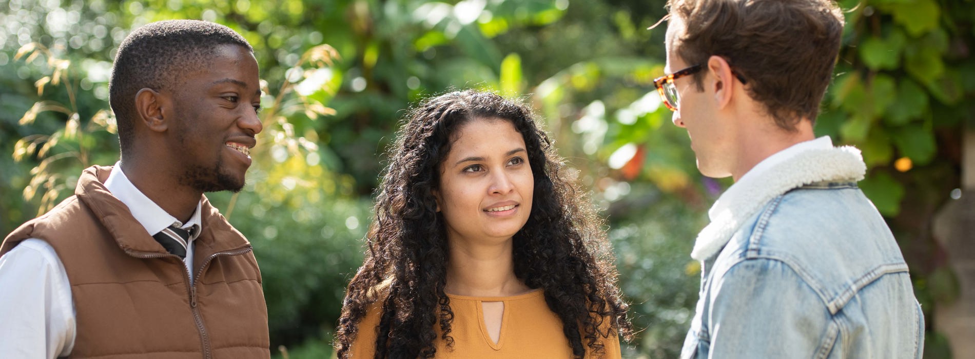 An image of three Rhodes Scholar students standing together outside on a bright, sunny day.