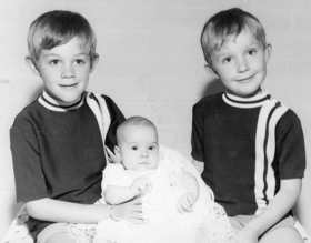 A black-and-white picture of two young boys holding a Elle as a toddler