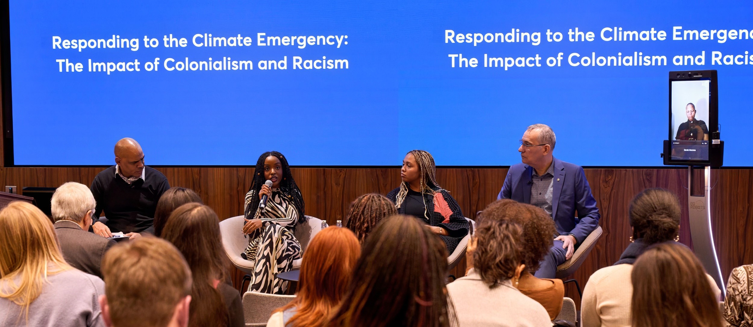4 panellists in person and 1 joining via a robot, in front of an audience at Rhodes House