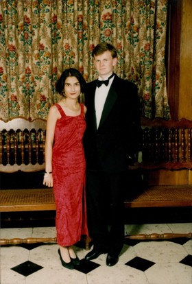 The picture shows Mark in a black suit. Standing next to him is a young woman in a red dress.