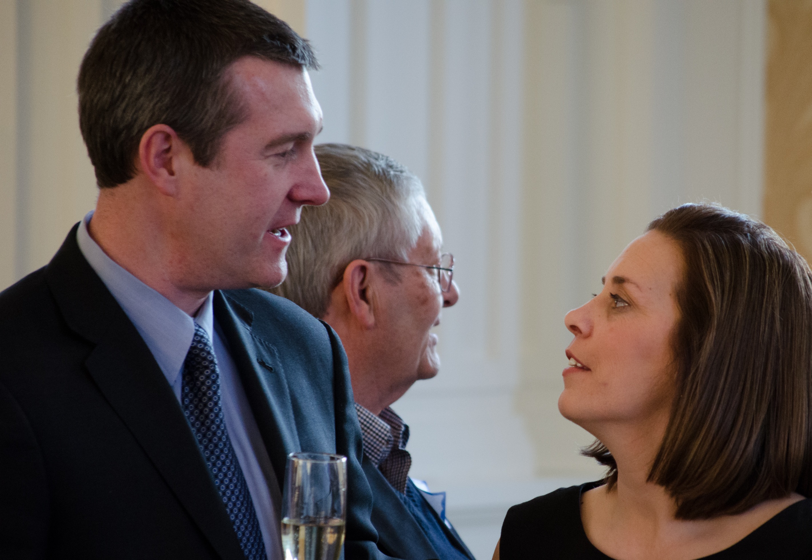 Dayne is pictured at the left in conversation with his wife. Between them we see another man who is engaged in a conversation with someone unpictured.