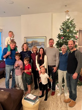 Large family photo of Geza's family, in a living room with Christmas tree in the background.