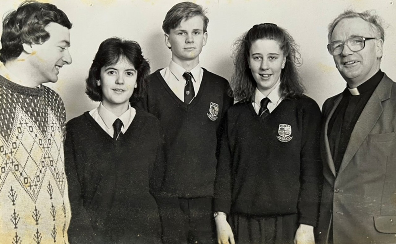 This black-and-white picture shows a group of students in uniforms with two teachers on their sides.