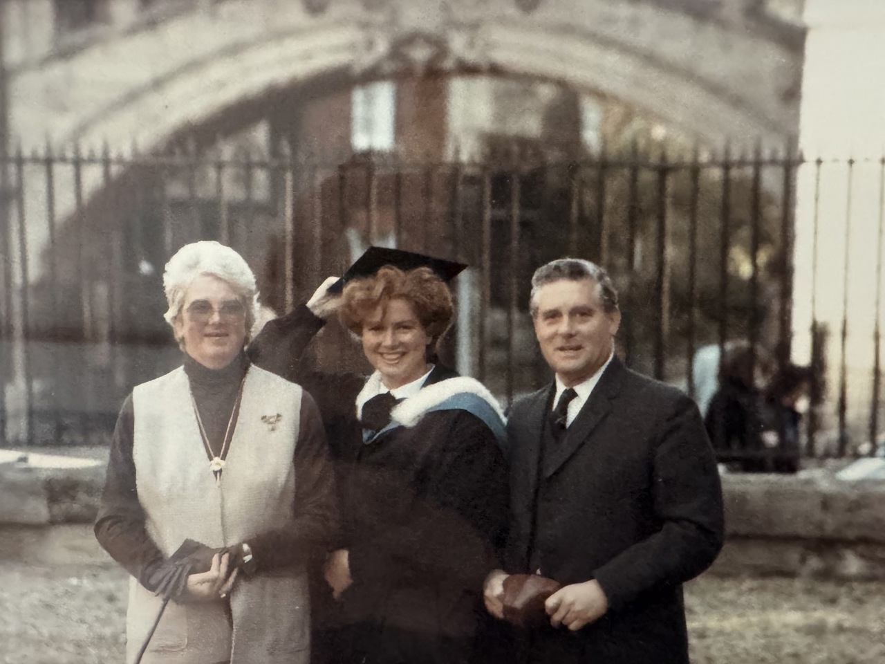 A picture of Elizabeth standing between her parents and wearing a graduation gown