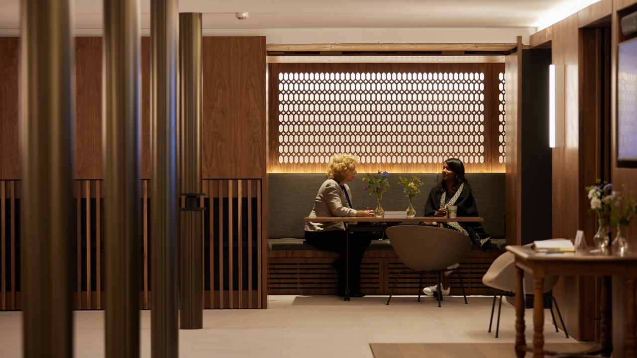 Conference Foyer nooks with tables and chairs. Two guests are seated in the nook.