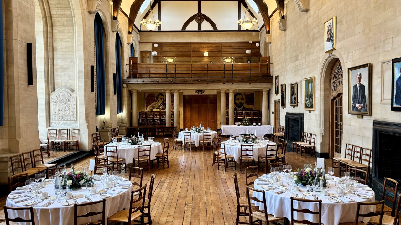 McCall MacBain Hall set up for a served dinner with round dining tables laid with white cloths.