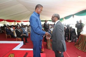 Kenneth on a red carpet shaking hands with man.