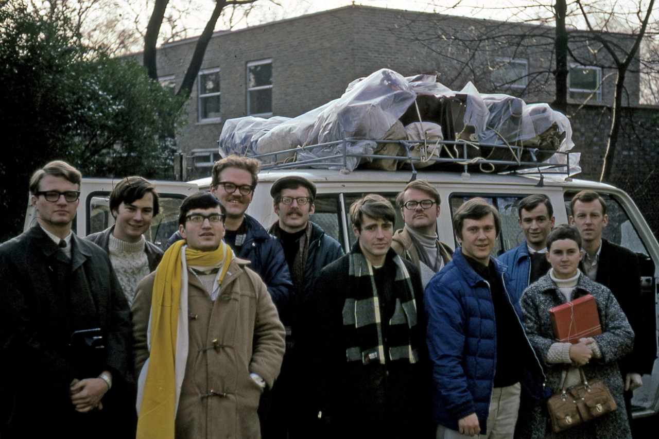 The picture shows a group of people in front of a van. They are all wearing warm clothing.
