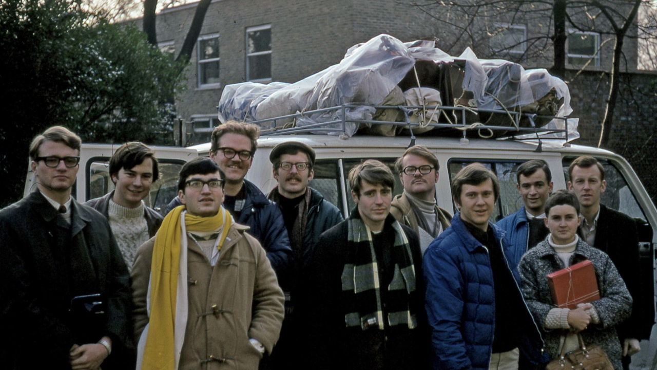 The picture shows a group of people in front of a van. They are all wearing warm clothing.