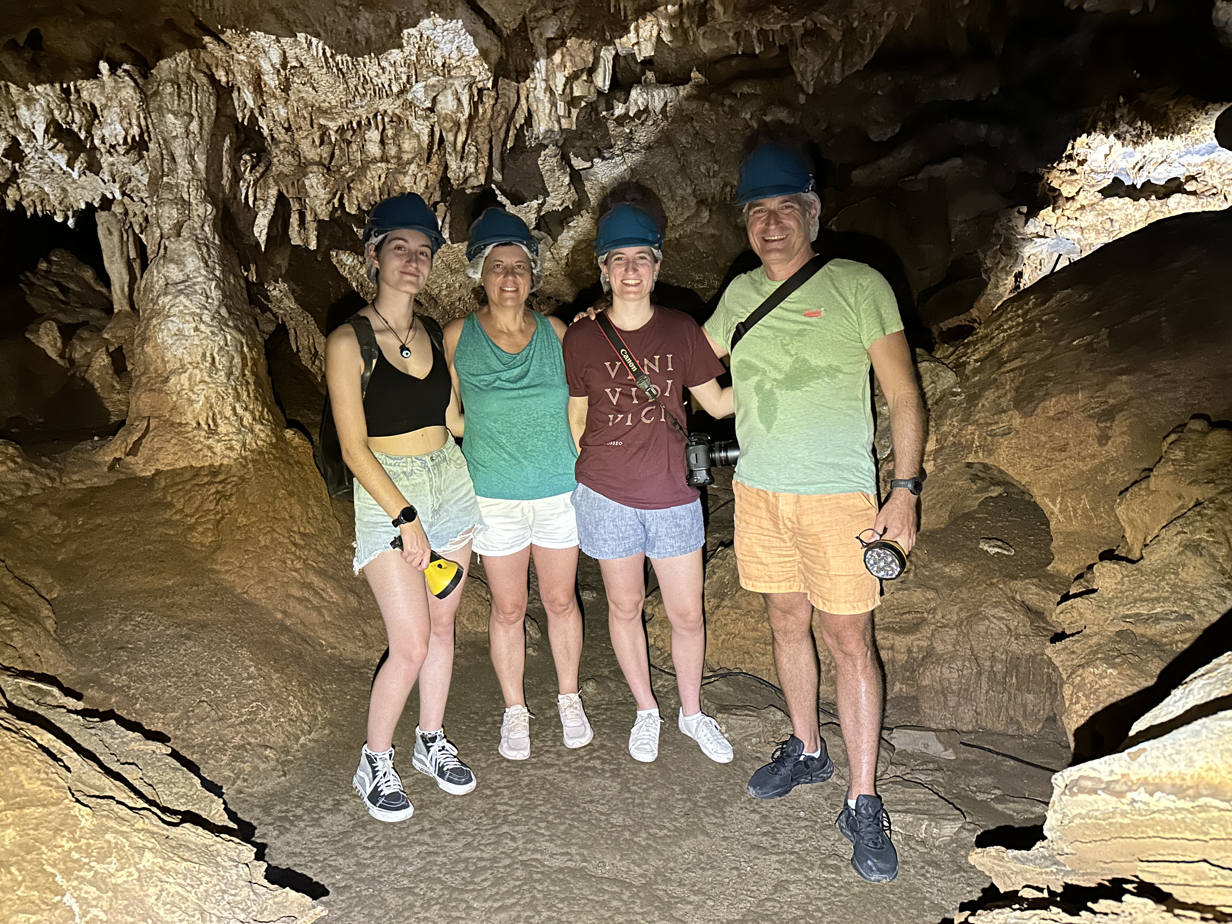 Agyris is stood with his wife and 2 daughters. They are all in a cave and wearing helmets.