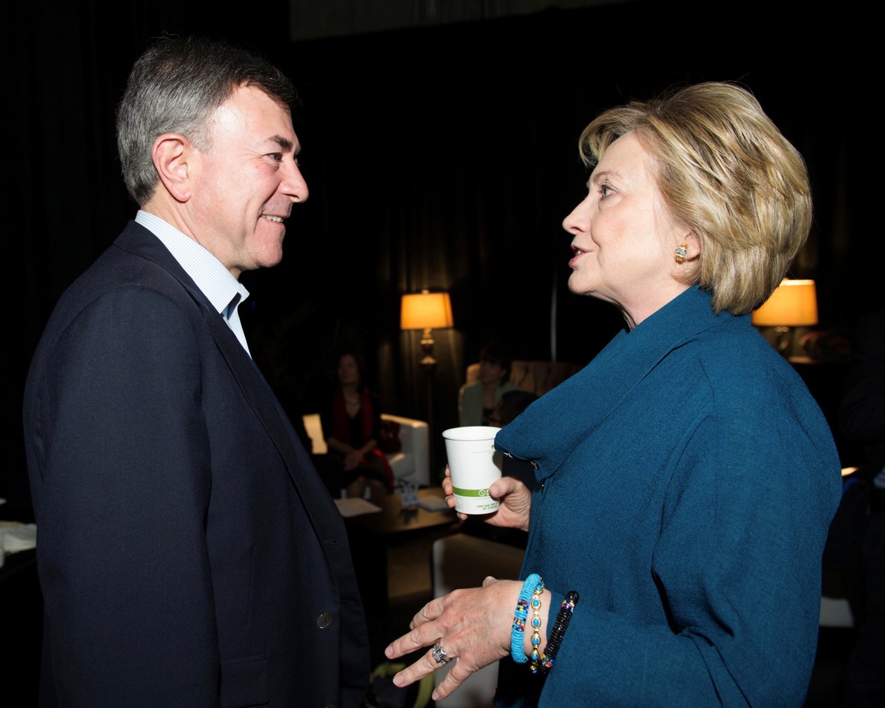 Bob and Hilary facing each other, in formal clothes, with Hilary speaking to him whilst Bob smiles.
